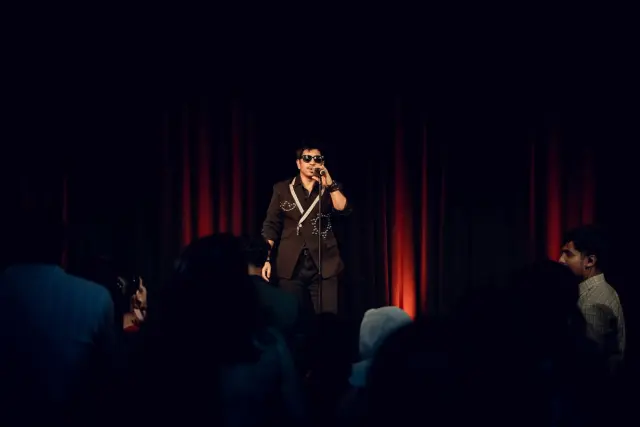 Prakash Saput singing in a spotlight before the red curtains